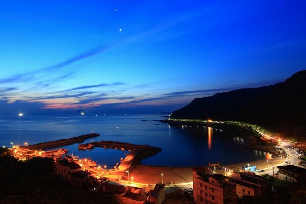 Ville de nuit au bord de la mer. Coucher du soleil