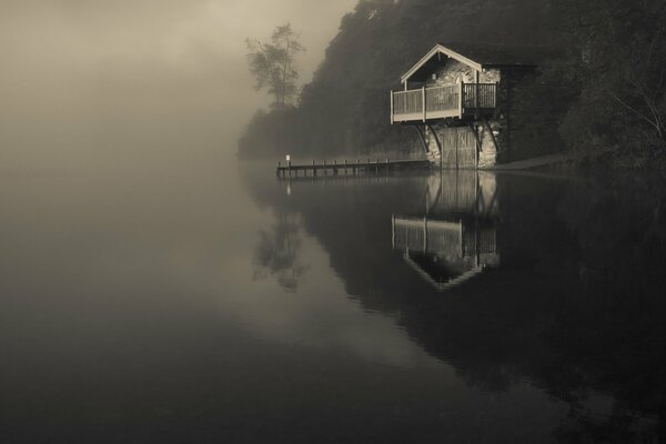 Lac dans le brouillard avec une maison solitaire