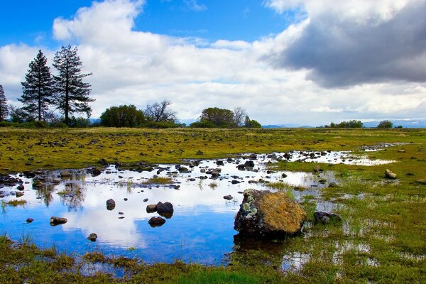 Flaque d eau au milieu du champ et au loin de la montagne