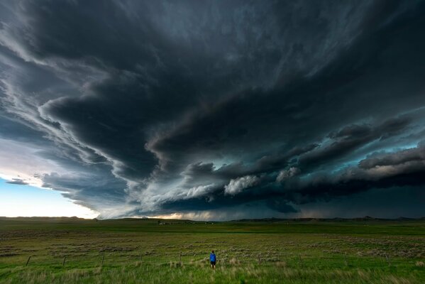 Homme dans un champ sous un ciel sombre et orageux
