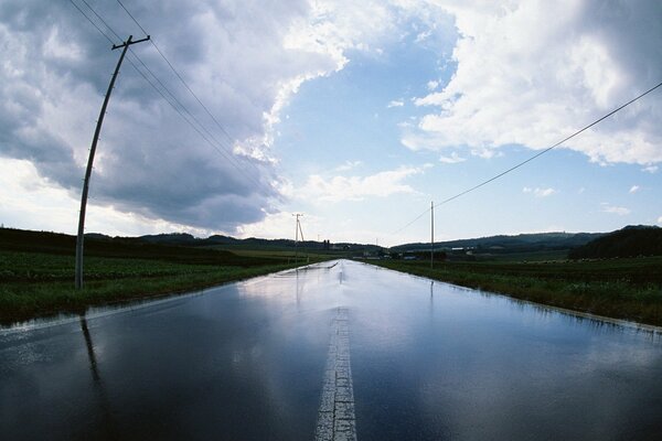 Route allant à l horizon, avec des poteaux sur les accotements et un ciel avec de gros nuages