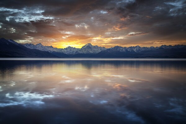 Reflet des nuages dans le lac sur fond de sommets enneigés