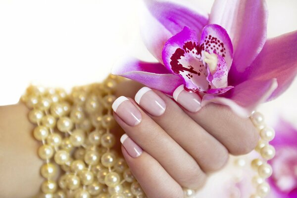 Main féminine avec manucure tenant une fleur