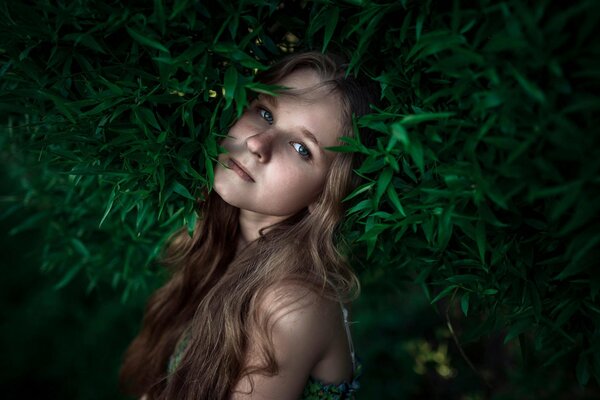 Fille aux cheveux longs avec des taches de rousseur au milieu de la verdure