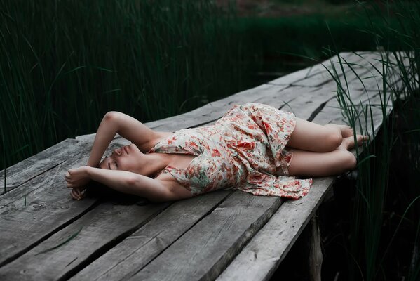 Jeune fille au repos sur un pont sur la rivière