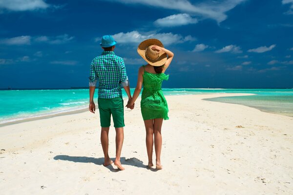 Sous les tropiques, un couple se promène sur la plage parmi les palmiers