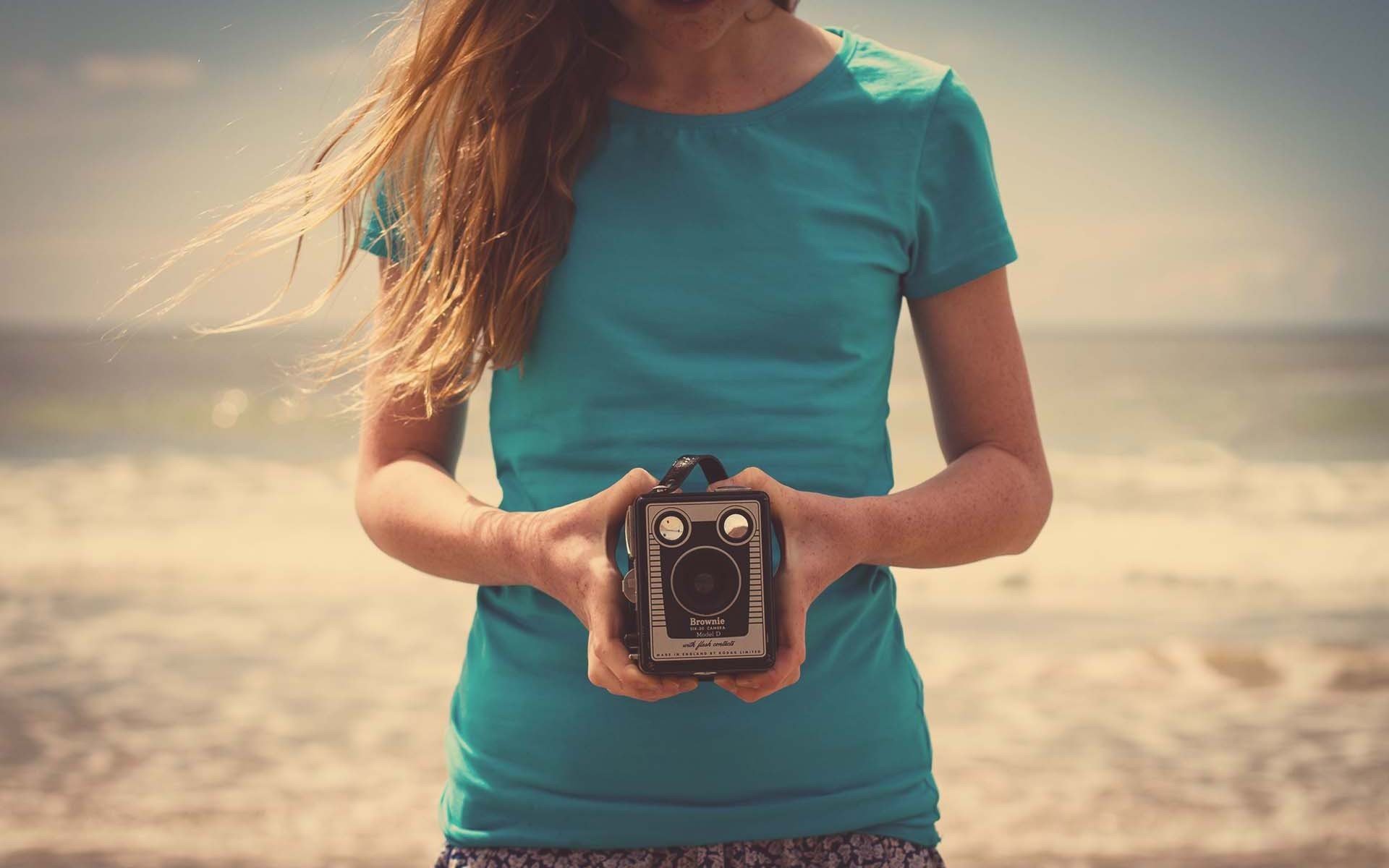 humeur fille cheveux noirs nature plage sable mains appareil photo appareil photo fond. fond d écran fond d écran