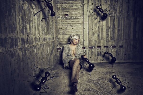 Fille assise sur le sable dans la Grange avec d énormes fourmis