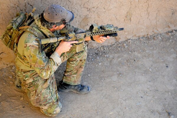 Soldat en camouflage accroupi et vise avec un fusil