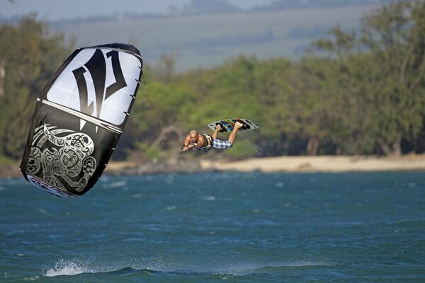 Surfeur vole au-dessus de la mer, tenant un parachute