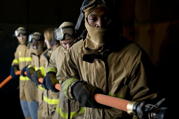 Cinq pompiers tiennent le tuyau